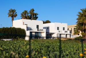 ein weißes Haus mit Palmen und einem Blumenfeld in der Unterkunft Casa B, Room 6 - Palm Kite Paradise in Marsala
