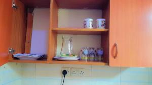 un meuble de cuisine avec un bocal, des assiettes et des tasses dans l'établissement Hellens homes, à Mombasa