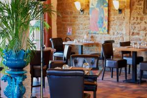 バゼイユにあるLogis Auberge du portのテーブルと椅子、青い花瓶のあるレストラン
