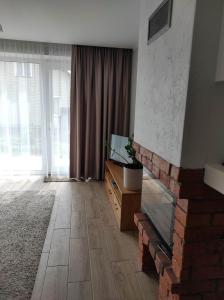 sala de estar con chimenea de ladrillo y TV en Apartamentai G&G, en Jurbarkas