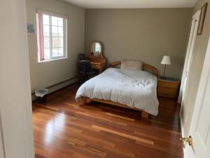 a bedroom with a bed and a wooden floor at SFU comfortable house in Burnaby