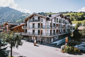 duży biały budynek z górą w tle w obiekcie 24 by AvenidA - Mountain Hotel w Kaprunie
