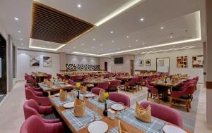 Click Hotel Aurangabad في أورانغاباد: مطعم بطاولات خشبية وكراسي حمراء