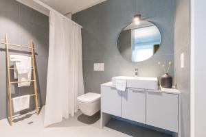 ein Badezimmer mit einem weißen Waschbecken und einem Spiegel in der Unterkunft Alpenblick Bern - kind of a hotel in Bern