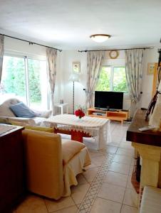 a living room with a couch and a tv at Naturstein-Mediterranhaus mit Gartenblick in Flogita