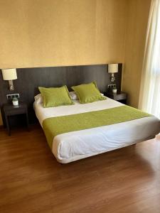 um quarto com uma cama grande e almofadas verdes em Hotel 1948 Manresa em Manresa