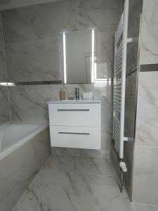 ein weißes Badezimmer mit einem Waschbecken und einer Badewanne in der Unterkunft Apartmán Zelený dom 43 (2) in Banská Štiavnica