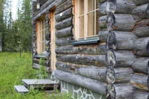 una casa de madera con ventanas y un banco al lado en Magic of Aarnilampi Pond en Luosto