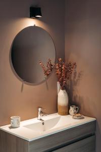 a bathroom sink with a mirror and a vase with flowers at le chalet de Plainpalais in Les Déserts