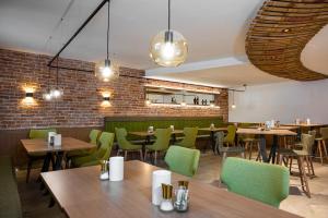 a restaurant with wooden tables and green chairs at Weingut Ferdl Denk in Weissenkirchen in der Wachau