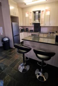 a kitchen with two bar stools in front of a counter at Klein Bosveld Guest House in eMalahleni