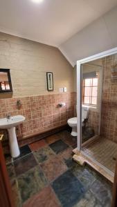 a bathroom with a shower and a toilet and a sink at Klein Bosveld Guest House in Witbank