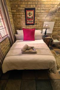 a bedroom with a large bed with a red pillow at Klein Bosveld Guest House in eMalahleni