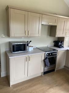 a kitchen with white cabinets and a microwave at Cosy small cottage in Wirral Merseyside with kitchen 