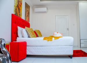 a bedroom with a large white bed with a red headboard at Eagles Nest Self-Catering Apartments in Gaborone