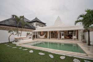 eine Villa mit einem Pool und einem Haus in der Unterkunft The White Joglo, feel the sea breeze from stylish 3BDR Villa W/Pool. in Canggu