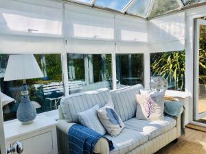 a conservatory with a couch in a room with windows at Secluded Spacious Garden Suite in Chichester