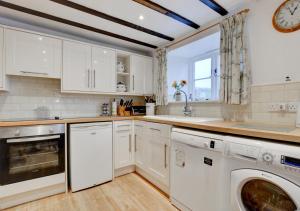 a kitchen with white cabinets and a washer and dryer at Lukes House in Askrigg