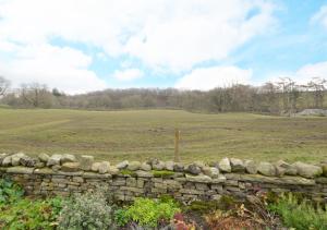 a stone wall with a field in the background at Lukes House in Askrigg