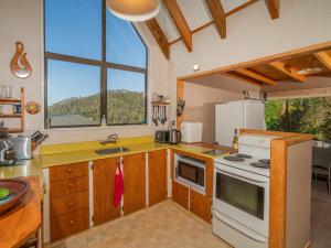 a kitchen with a stove top oven next to a window at Hahei Horizon - Hahei Holiday Home in Hahei