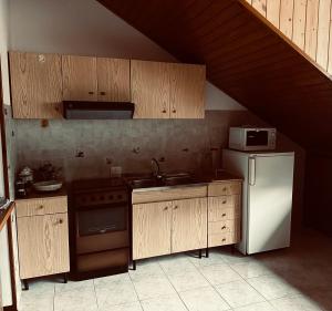 een keuken met houten kasten en een witte koelkast bij Tess’home in Pontebba
