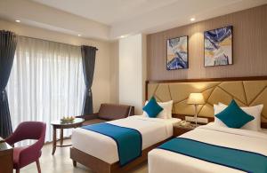 a hotel room with two beds and a desk at Click Hotel Aurangabad in Aurangabad