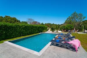 a swimming pool with loungers and chairs in a yard at Villa Iasama in Rhodes Town