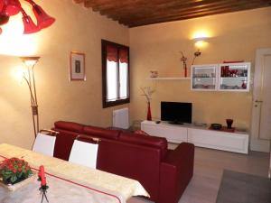 een woonkamer met een rode bank en een televisie bij Ca' Delle Maschere in Venetië
