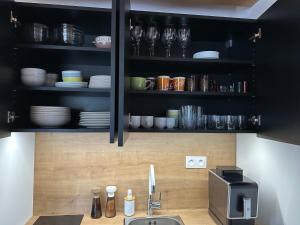 a kitchen with black cabinets and a sink with dishes at Apartmánik pri Zubačke in Tatranska Strba