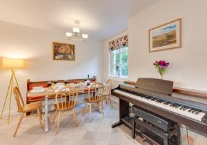 a dining room with a piano and a table and chairs at Long View in Kettlewell