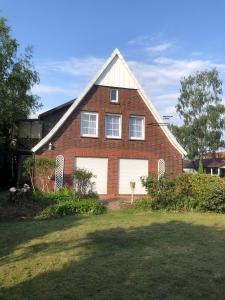a red brick house with two white garage doors at Wohnen im Alten Land in Grünendeich