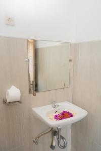 uma casa de banho com lavatório, espelho e flores em ABIAN HOUSE NUSA PENIDA em Batununggul