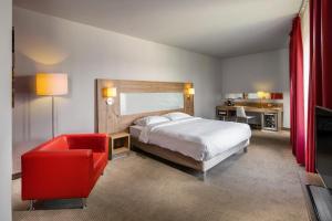 a bedroom with a bed and a red chair at Quality Hotel Ostrava City in Ostrava