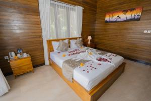 um quarto com uma cama com flores vermelhas em ABIAN HOUSE NUSA PENIDA em Batununggul