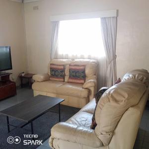 een woonkamer met een bank en een tafel bij Neat and cosy cottage with pool - 2103 in Harare