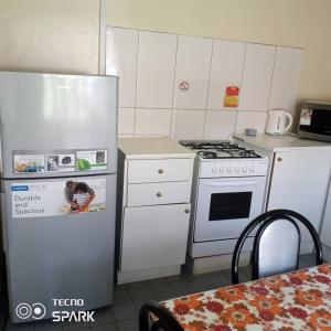 una pequeña cocina con electrodomésticos blancos y una mesa en Neat and cosy cottage with pool - 2103 en Harare