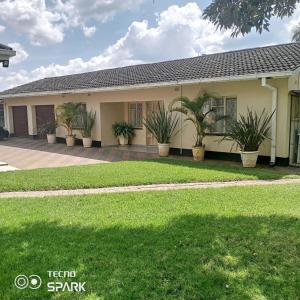a house with potted plants in front of it at Neat and cosy cottage with pool - 2103 in Harare