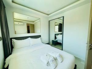 une chambre avec un lit blanc avec deux serviettes dessus dans l'établissement Arcadia Beach Continental 1-Bedroom Condo, à Pattaya (sud)