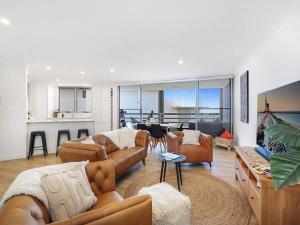 a living room with leather couches and a kitchen at Lavish 3-bedroom ocean apartment in Wollongong in Wollongong