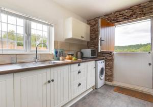 a white kitchen with a sink and a dishwasher at Little Haven in Easby