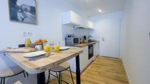 - une cuisine avec une table en bois, des chaises et du jus d'orange dans l'établissement Le Noir’issime - Appartement tout équipé à Niort, à Niort