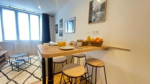 une cuisine avec une table, des chaises et des oranges. dans l'établissement Le Noir’issime - Appartement tout équipé à Niort, à Niort
