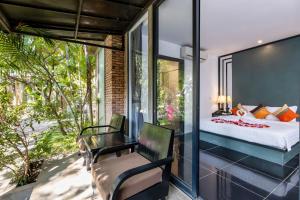 1 dormitorio con 1 cama y 1 silla en el balcón en Maison Gen Angkor, en Siem Reap