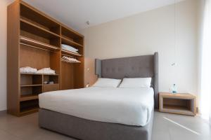 a bedroom with a large white bed and wooden shelves at Mosella Suite Hotel in Sottomarina
