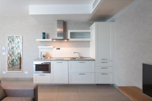 a kitchen with white cabinets and a sink at Mosella Suite Hotel in Sottomarina