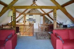 uma sala de estar com dois sofás vermelhos e uma cozinha em West Hollowcombe Farm Cottages - full site booking em Dulverton