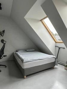 ein Schlafzimmer mit einem Bett im Dachgeschoss mit einem Fenster in der Unterkunft Raguvos Apt. in Kaunas