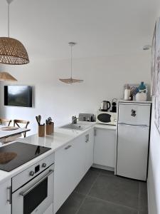 eine Küche mit weißen Arbeitsflächen und einem weißen Kühlschrank in der Unterkunft L'Opale - Le White in Les Attaques