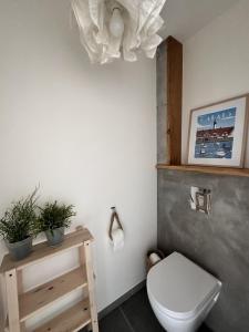 uma casa de banho com um WC branco e uma mesa de madeira em L'Opale - Le White em Les Attaques