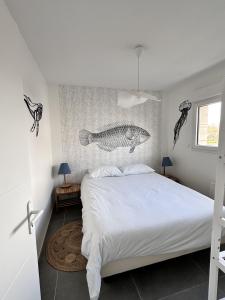 ein Schlafzimmer mit einem Bett mit einem Wandbild aus Fisch in der Unterkunft L'Opale - Le White in Les Attaques